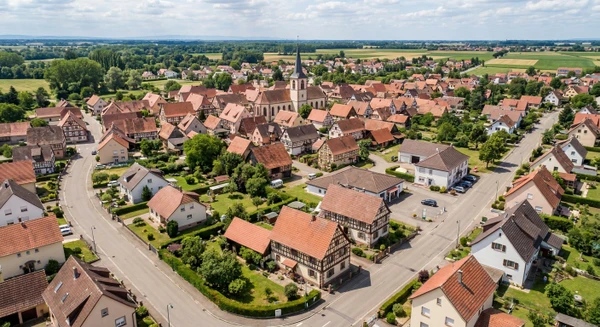 Photographie a&eacute;rienne ou vue panoramique d'une commune du Bas-Rhin (Fegersheim), montrant des habitations r&eacute;sidentielles typiques de la r&eacute;gion avec toitures, rues calmes et environnement p&eacute;riurbain. L'image doit transmettre un sentiment de proximit&eacute; et d'accessibilit&eacute; locale, repr&eacute;sentative d'une petite commune alsacienne o&ugrave; intervient l'entreprise de r&eacute;novation.