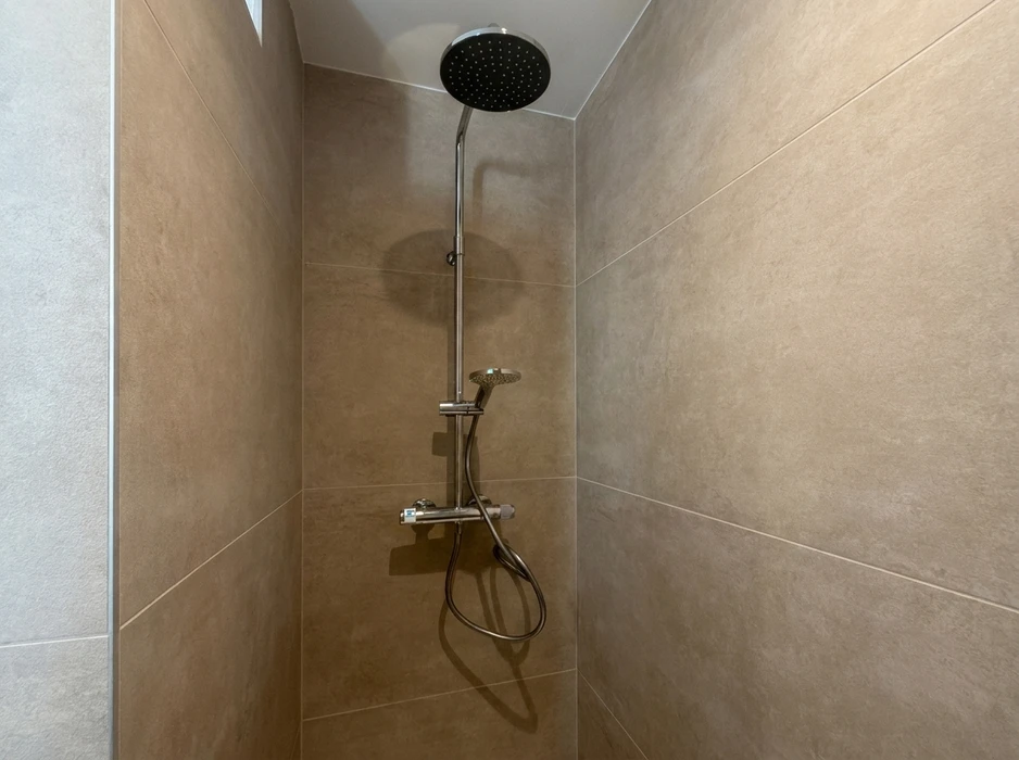 Intérieur de chantier, ouvrier en gants de protection jaunes utilisant une scie sauteuse électrique pour découper des lames de parquet stratifié